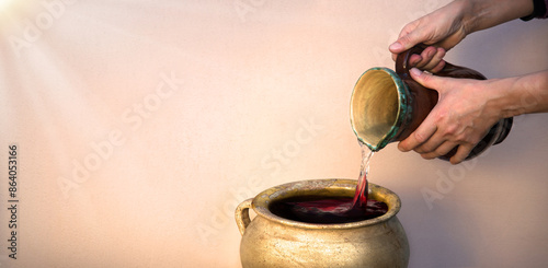 A hand holds a clay jar and pours water