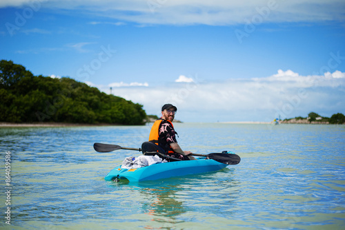 tourist in kayak with paddle next to pelicans flying over the sea in a tropical bay