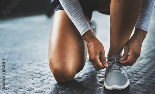 Gym, hands and person tying shoes to start exercise, training or workout at health club on floor. Legs, athlete and tie lace on sneakers to prepare or getting ready for sport, fitness or wellness