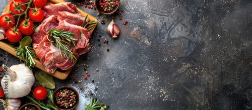 Ingredients for marinating meat including raw pork shoulder, spices, dry herbs, onions, garlic, rosemary, bay leaf, nutmeg, pepper mix, and tomatoes on a vintage wooden board with a stone background