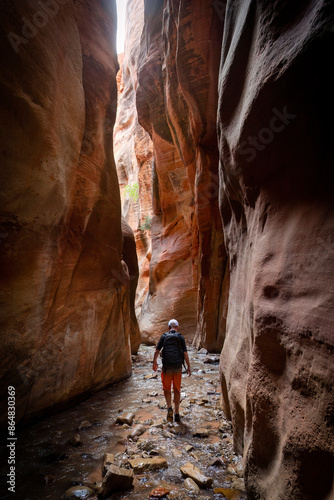 Young man walking through a scenic slot canyon near Zion National Park in Utah. Hiking Adventure in the beautiful Southern Utah region - a great outdoor recreation spot.