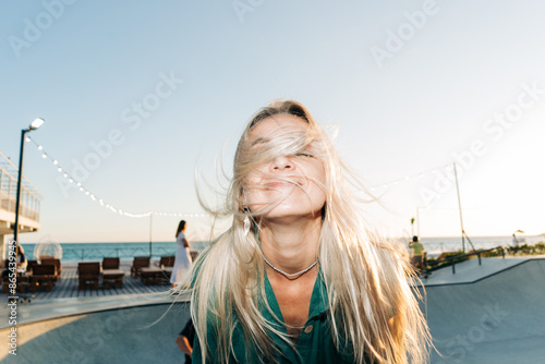 Wind in the hair. Lifestyle flash motion portrait of a cheerful woman with long blond hair.