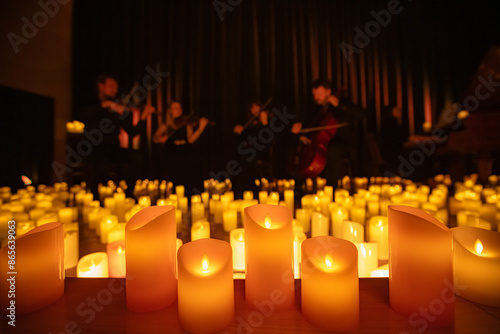 blurred symphonic orchestra on stage with lots of candles