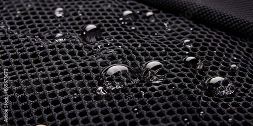 Closeup of black waterproof fabric with water droplets, highlighting its protective and moisture-resistant properties in a detailed view