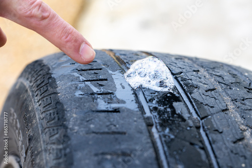 Finger pointing at soap bubbles on tire used to find hole