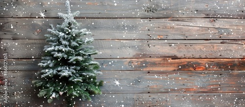 Festive Christmas fir tree set on a wooden backdrop scattered with delicate snowflakes, perfect for a copy space image.