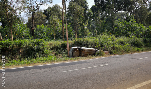 An Accident scene where a Sedan car has overturned and fallen into a road side ditch in the forest area of Coorg district in India.