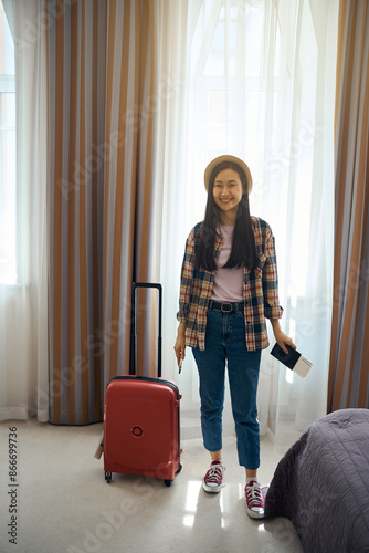 Contented traveler posing for camera in hotel room on arrival