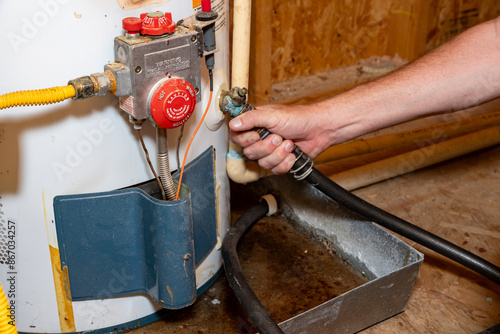 Plumber's hand connecting drain hose to water heater