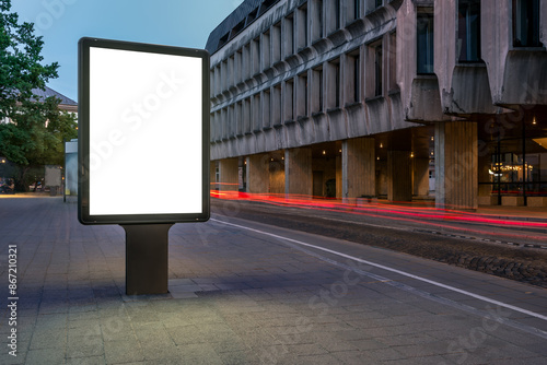 Street Billboard Mockup On Sidewalk At Night. Outdoor Advertising Lightbox with Car Light Trails In The Background