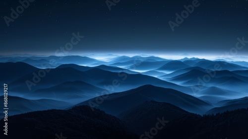 A misty, blue-hued mountain range bathed in the soft light of dawn. The peaks disappear into the clouds, creating a sense of mystery and grandeur.