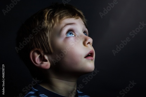 Young boy looking up with wonder and amazement on dark background