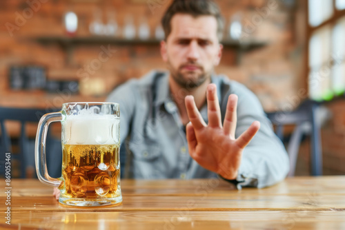 A man is sitting at a table with a glass of beer in front of him