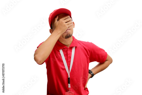 An annoyed Asian delivery man or courier is facepalming, hiding his face in frustration and embarrassment due to a delivery mistake. Isolated on a white background