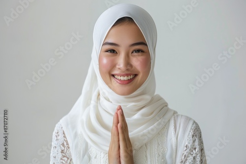 Smiling Asian woman in traditional attire showing namaste gesture.