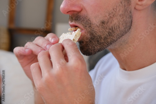 young bearded 30-year-old man finds joy, eating gluten-free rice cracker, guilt-free indulgence, mindful eating, healthy snacking, nutritious snack