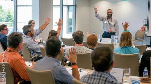 People are sitting in a room listening to a man speak. The man is standing in front of a white board with a marker in his hand. He is looking at the audience and smiling. The audience is made up of