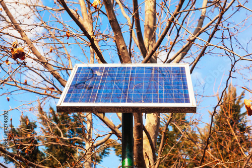 A solar panel is installed on a street lamp post in a park.