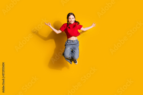 Full length portrait of cute little girl jump meditate wear t-shirt isolated on yellow color background