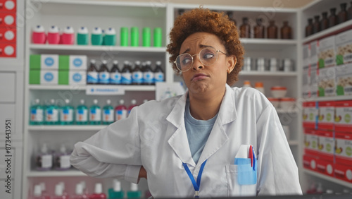 African american pharmacist woman with skeptical expression standing in pharmacy store indoors.