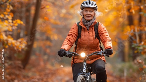 Senior woman performing a wheelie on a BMX bike in a park filled with autumn leaves Stock Photo with copy space