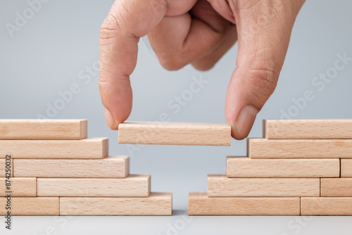 Closeup hand put a wooden piece between the gap of the wall built with wood toy, solution to solve the gap problem