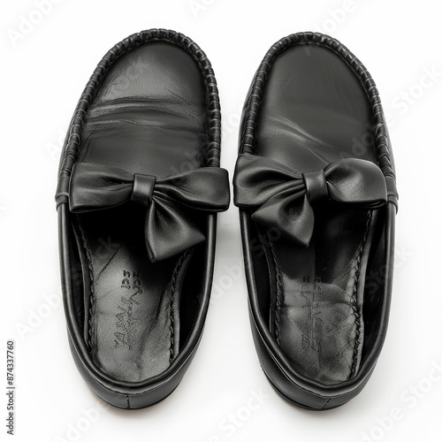 Comfortable black leather moccasins with a bow detail, isolated on white background.