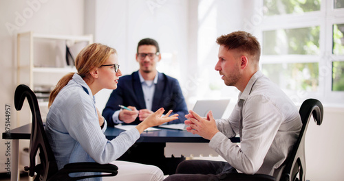 Professional lawyers mediating a tense argument between a young Hispanic couple