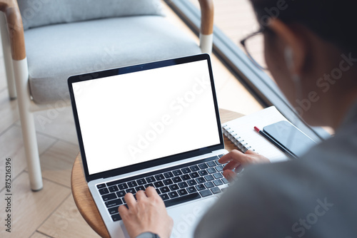 Mockup blank white screen laptop computer. Woman working, using laptop computer on wooden table with empty screen for advertising, template for web deign or social media marketing, freelance work