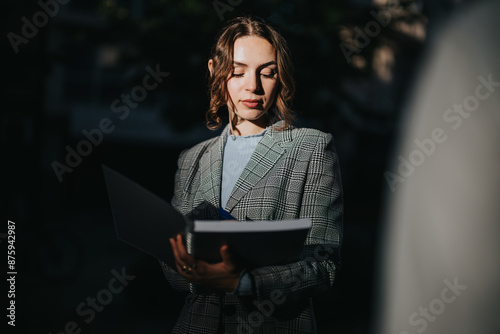 Young business associate reviewing documents and strategizing during a meeting in an urban city setting. Focused on brainstorming new ideas and solutions.