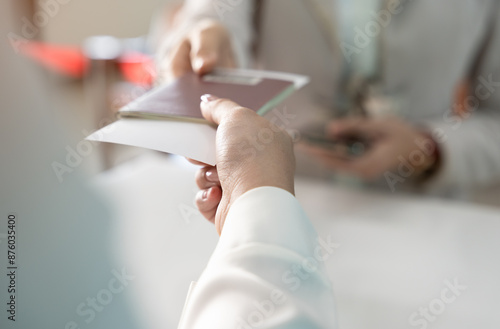 Businesswoman giving passport to airlines ground attendant or immigration office at airport departure gate or check in counter. Travel and vacation concept