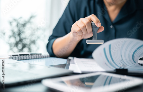 Banking officer stamped the document to approve the loan, finalizing the contract and solidifying the finance agreement, fundamental concept in business transactions. approve, loan, stamp, business.