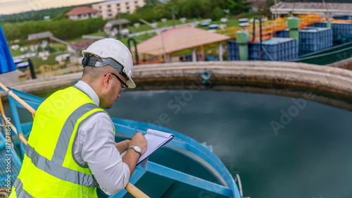 environmental engineer working at the wastewater treatment try to check the quality of the water in a tank and write donw the test result on a clipboard