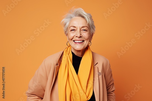 Cheerful senior woman in stylish clothes posing over orange background.