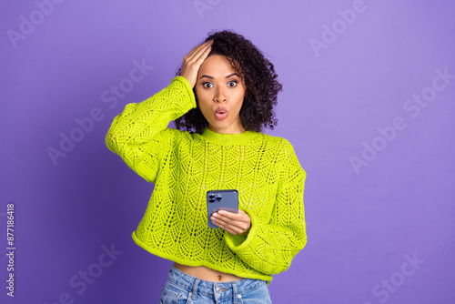 Photo of wavy hair american young girl touch head in green jumper using smartphone forgot password isolated on purple color background