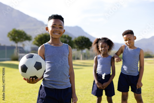 Portrait of happy african american schoolchildren playing football on field at school