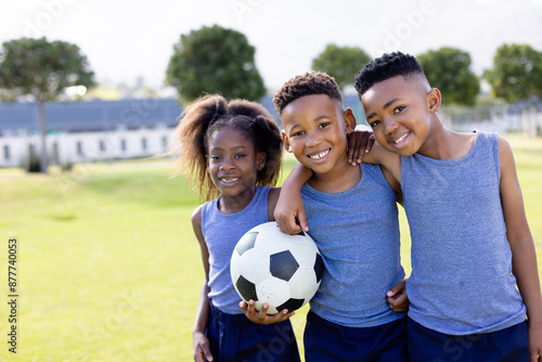 Portrait of happy african american schoolchildren playing football on field at school