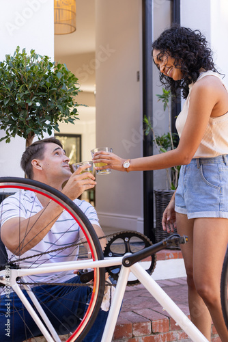 Fixing bicycle, young couple toasting with drinks, enjoying outdoor time together