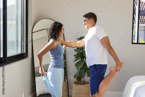 Stretching together, couple exercising in bedroom, smiling and enjoying fitness