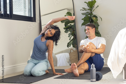 Stretching together, young couple practicing yoga on mats in cozy home setting