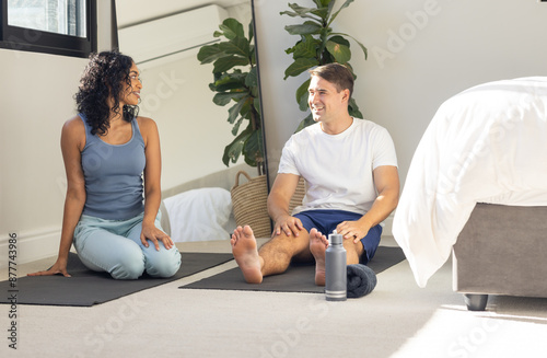 Practicing yoga, young couple sitting on mats and smiling at each other