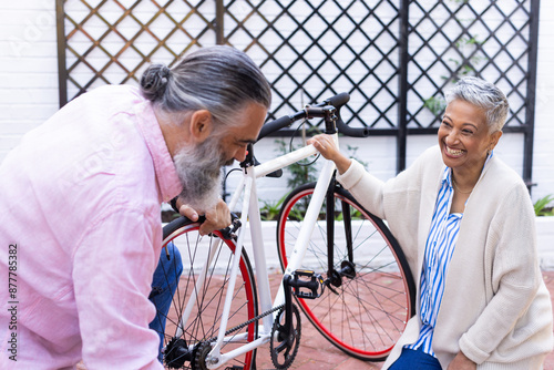 Fixing bicycle, senior couple enjoying outdoor activity together, smiling and bonding