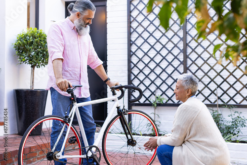 Senior couple with bicycle, discussing outdoor activity in front of house