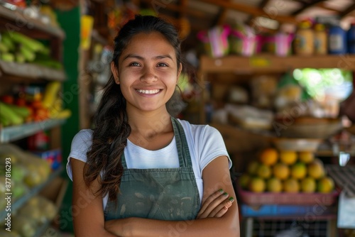 Young latin shopkeeper girl with arms crossed smiling happy