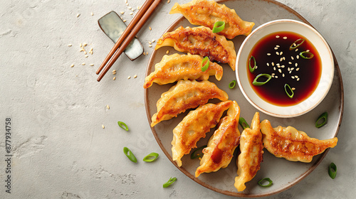  a top view scene showcasing a plate of fried Chinese gyoza accompanied by a small dish of soy sauce. 