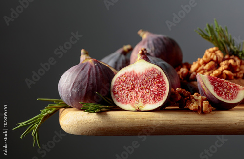 Figs, walnuts, and rosemary on a wooden table.