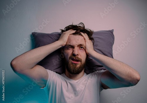 Top view man having trouble sleeping head on a pillow hands on the head 