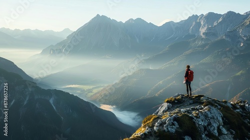 A hiker, standing on a mountaintop, with a breathtaking view of a valley bathed in morning light Soft light, misty mountains, focus on the sense of peace and awe