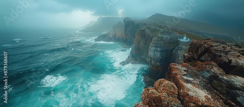 Stunning view of rugged coastal cliffs with powerful waves crashing against them under a dramatic, stormy sky.