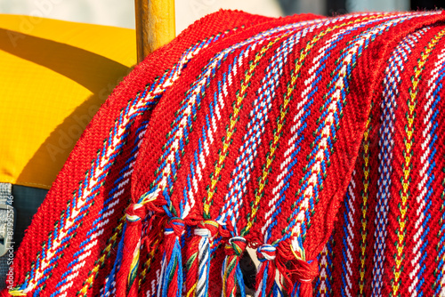 ceinture fléchée (traditional pattern) replica of the woven sash worn by voyageurs during the fur trade shot on a rail with orange pfd's and wooden canoe paddles room for text